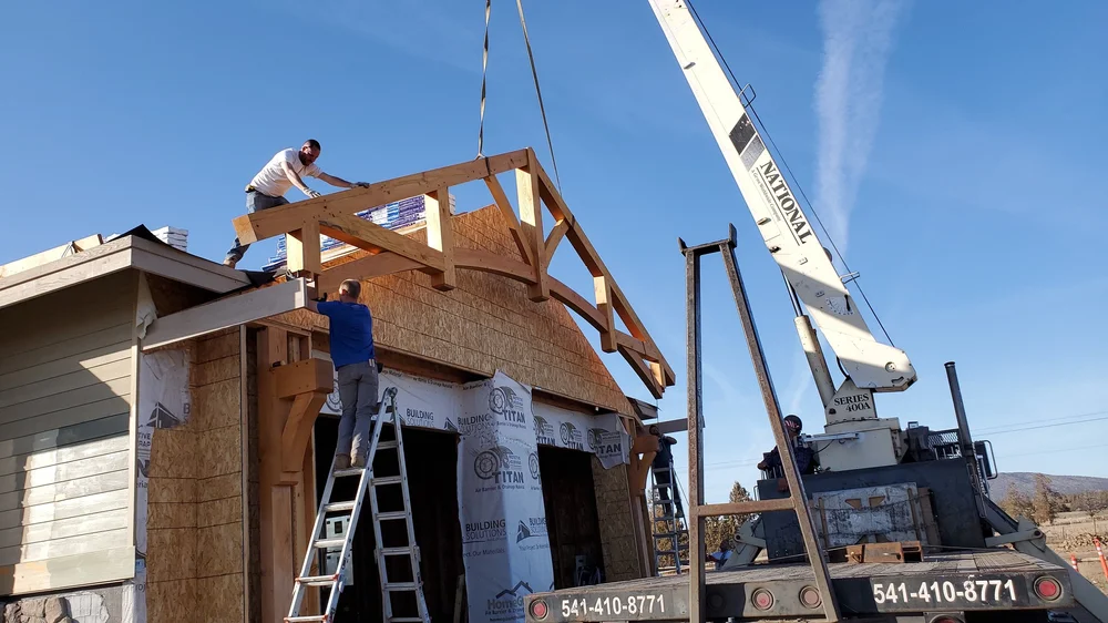 Our team installing a heavy timber outdoor beam on the front of the house under construction