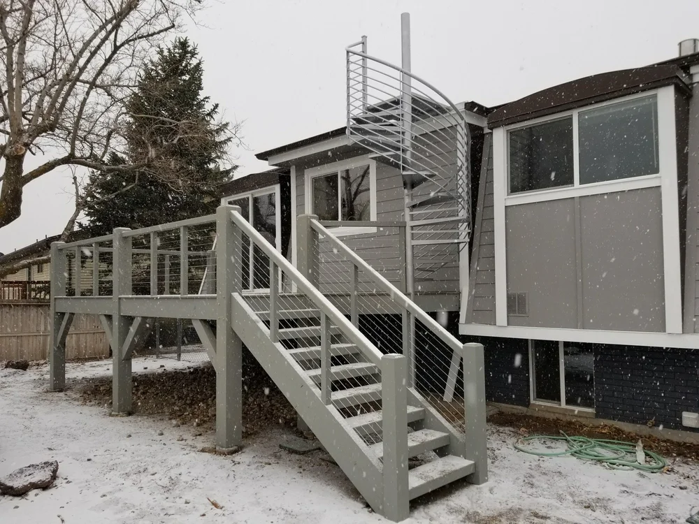 A back porch with a staircase leading to a deck using our timber frames and joinery as the foundation