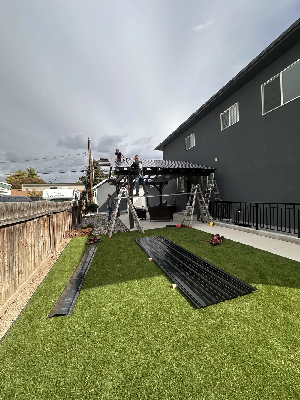 Our team installing a modern backyard pergola design with a metal roof