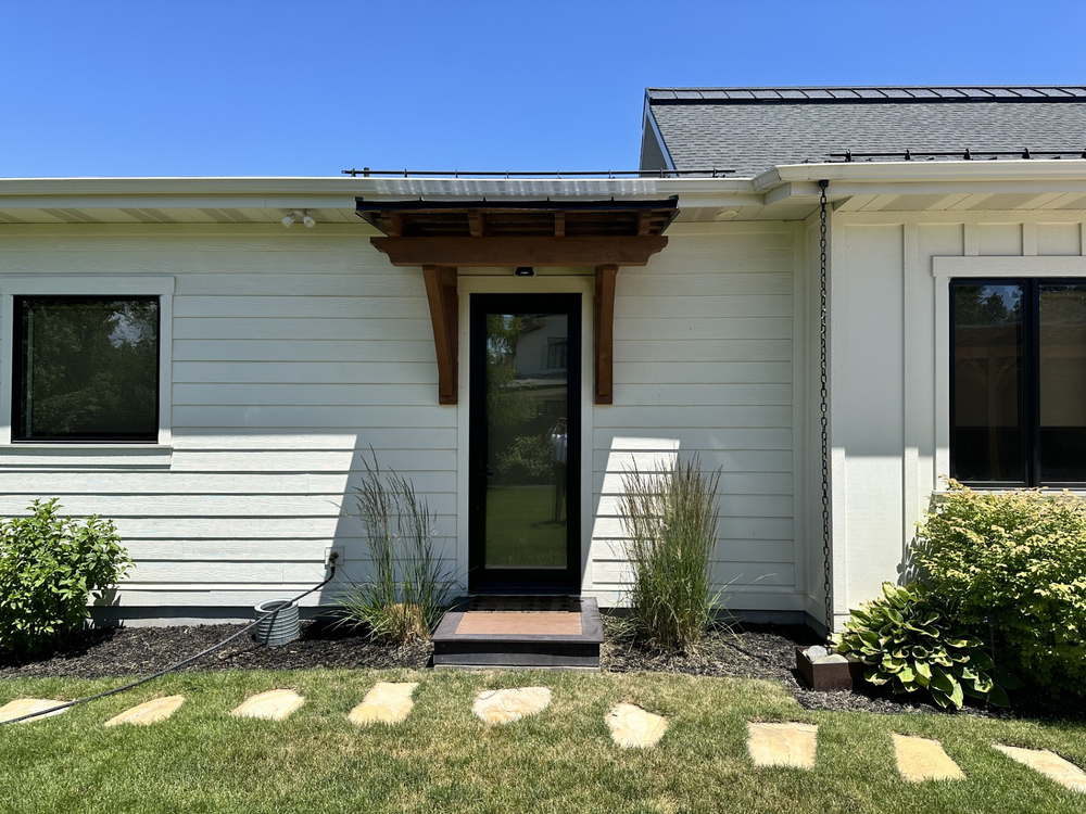 Exterior view of a modern house entrance and a small entry timber truss awning