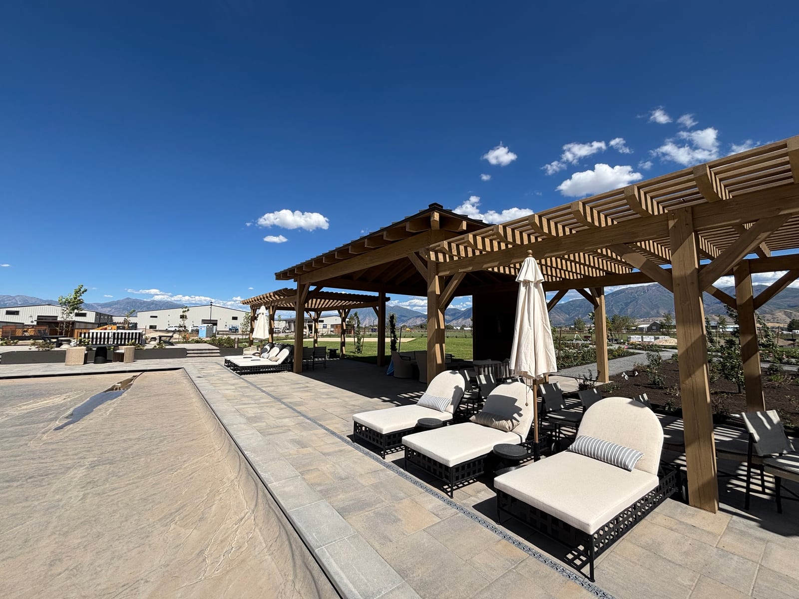 Timber pavilion and attached pergola shading a poolside patio with mountain views