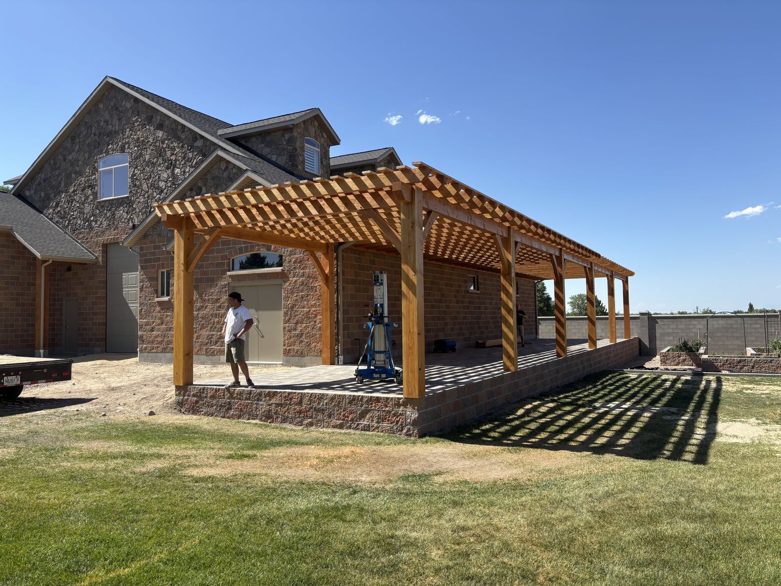 Large timber pergola spanning the length of a stone home